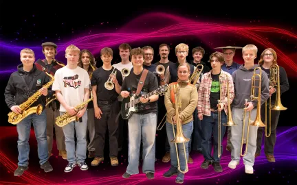 En gruppe folk med instrumenter st&aring;r sammen, et ungdomsstorband.