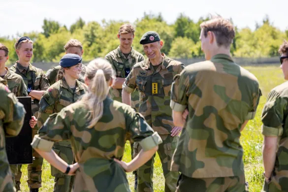 En gruppe personer i milit&aelig;r uniform som st&aring;r ute p&aring; gresset. 